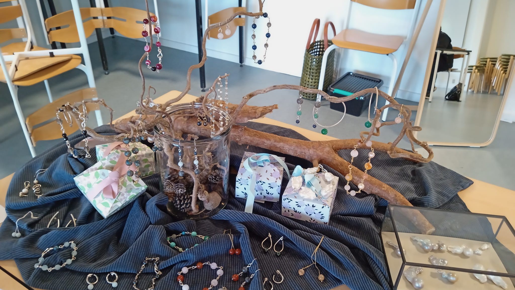 Udstilling af hjemmelavede smukker placeret på bord, i glasmontre og på troldhasselgren