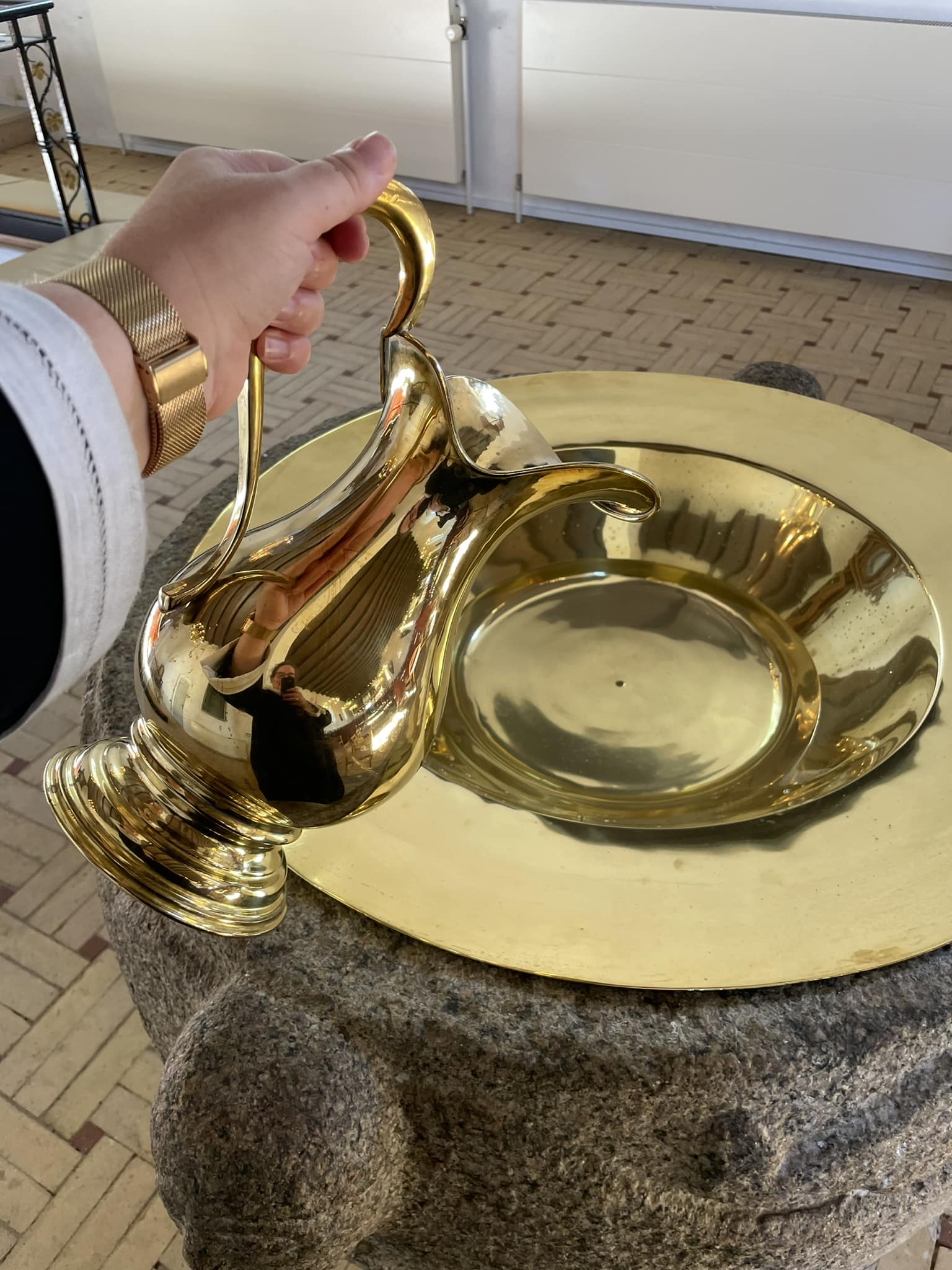 Præst hælder dåbsvand op i dåbsfad